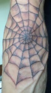 Spider web prison tattoo with blue-grey prison ink